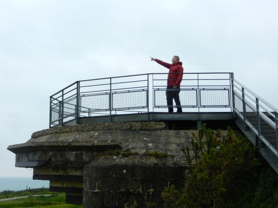 Standing on top of a German bunker, Tim points out the direction the Allies came from