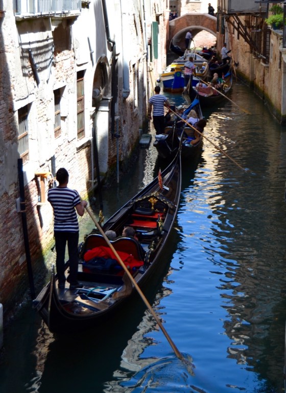 A line of gondoliers in a Venice canal